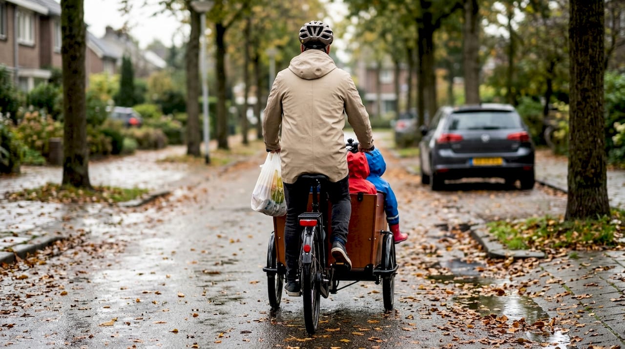 Een gezin rijdt samen met de elektrische bakfiets door hun rustige woonwijk.