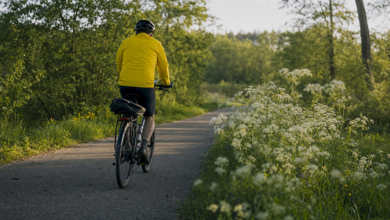 Een man fietst over een milieuvriendelijk Belgisch fietspad dat door het bos slingert.