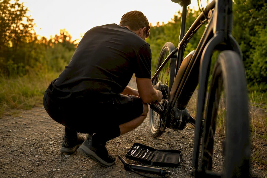 Man die de aandrijving van een e-bike van achteren inspecteert