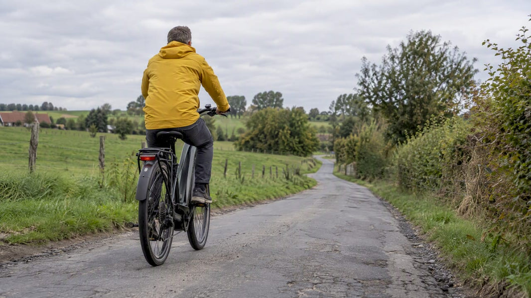 Man test e-bike op een landelijke weg in België